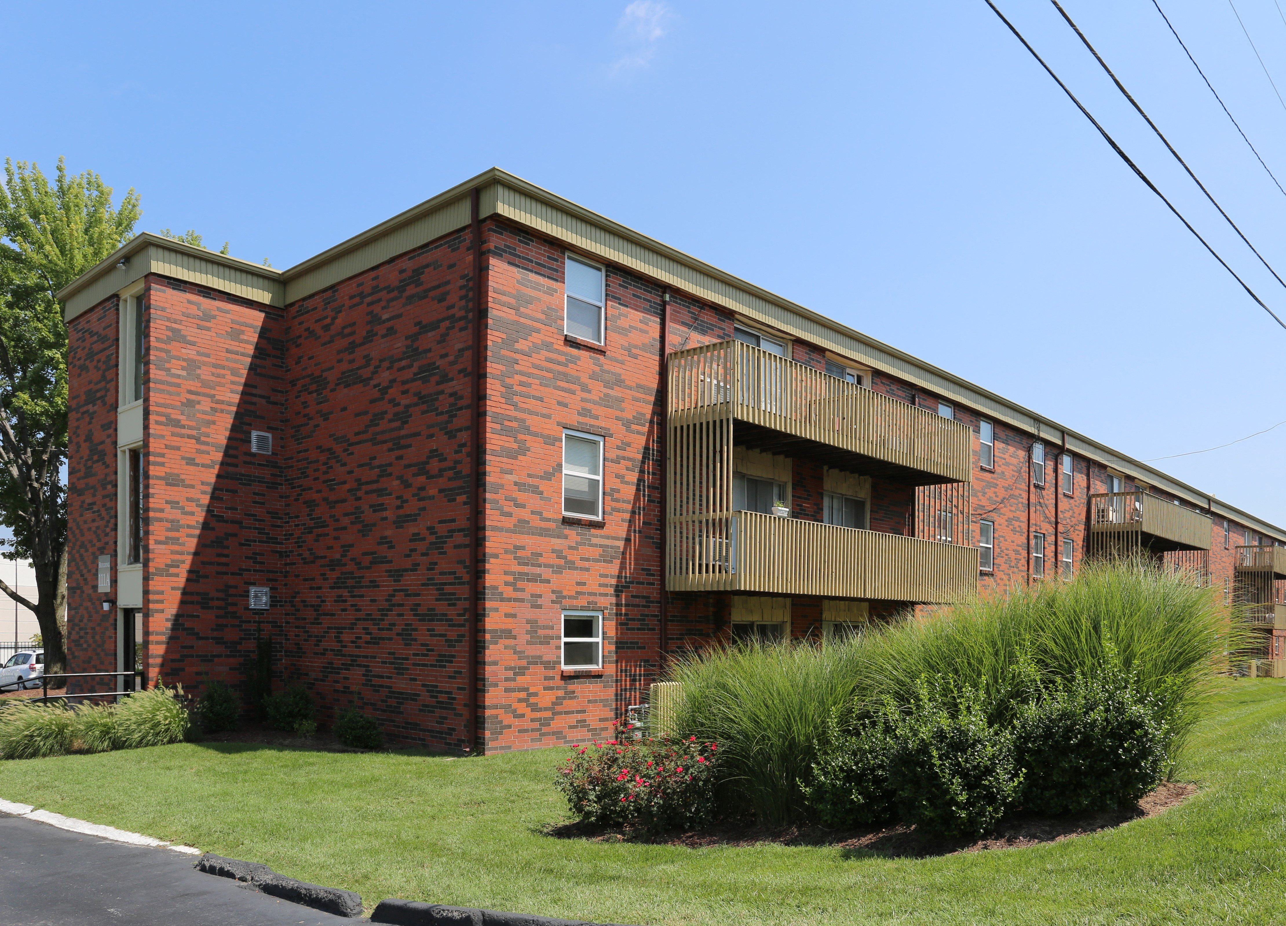 an exterior view of a red brick apartment building with balconies